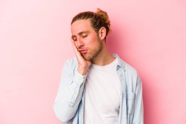 Pembe arka planda izole edilmiş genç beyaz adam sıkılmış, yorgun ve dinlenmeye ihtiyacı var..