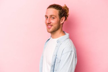 Pembe arka planda izole edilmiş beyaz bir adam. Kendine güveniyor. Kalçaları tutuyor..