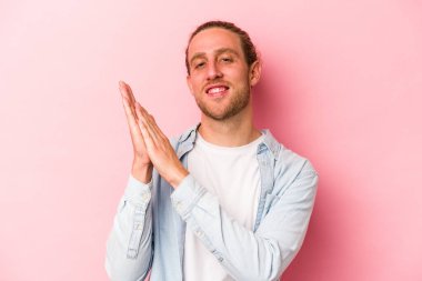 Pembe arka planda izole edilmiş genç beyaz adam enerjik ve rahat hissediyor, ellerini ovuşturuyor..