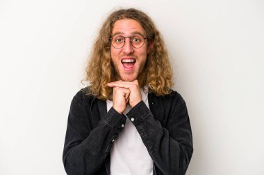 Beyaz arka planda izole edilmiş genç beyaz bir adam şans için dua ediyor, şaşırmış ve ağzını açıp önüne bakıyor..