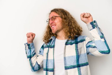 Beyaz arka planda izole genç beyaz adam özel bir günü kutluyor, atlıyor ve enerjiyle kollarını kaldırıyor..