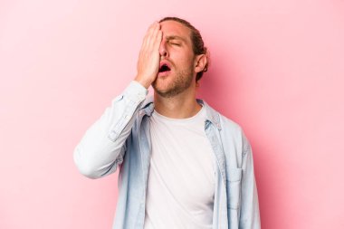 Pembe arka planda izole edilmiş genç beyaz adam yorgun ve uykulu..