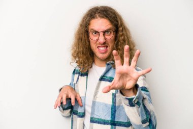 Beyaz arka planda izole edilmiş genç beyaz bir adam pençelerini kedi taklidi yaparken gösteriyor, agresif bir hareket..