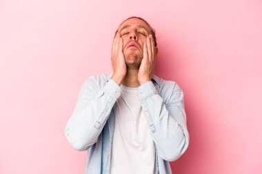 Pembe arka planda yalnız kalmış, ağlayan ve sızlanan genç beyaz bir adam..