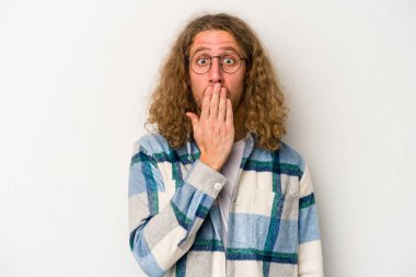 Beyaz arka planda izole edilmiş genç beyaz adam şok olmuş, ağzı ellerle kaplanmış, yeni bir şey keşfetmeye hevesli..