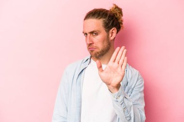 Pembe arka planda izole edilmiş genç beyaz bir adam tiksinti belirtisi gösteren birini reddediyor..