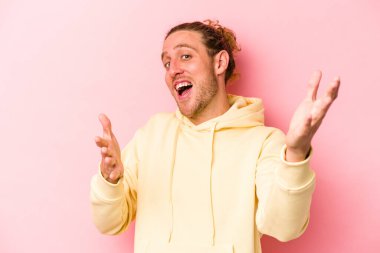 Pembe arka planda izole edilmiş genç beyaz adam kameraya sarıldığı için kendinden emin hissediyor..