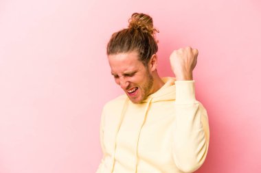 Pembe arka planda soyutlanmış, tasasız ve heyecanlı genç bir beyaz adam. Zafer konsepti.