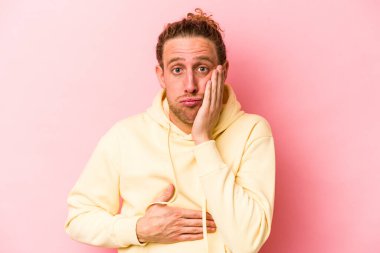 Pembe arka planda izole edilmiş genç beyaz adamın yanakları şişer, yorgun bir ifadesi vardır. Yüz ifadesi kavramı.