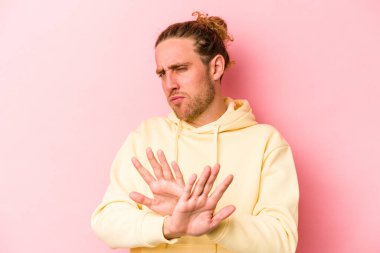 Pembe arka planda izole edilmiş genç beyaz adam inkar jesti yapıyor.