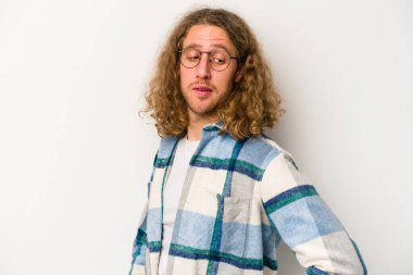 Beyaz arka planda izole edilmiş genç beyaz adam gülümseyen, neşeli ve keyifli bir tarafa bakıyor..