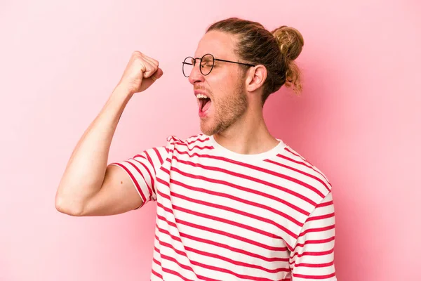Pembe arka planda izole edilmiş genç beyaz bir adam zaferi, tutkuyu ve coşkuyu kutluyor, mutlu bir ifade..