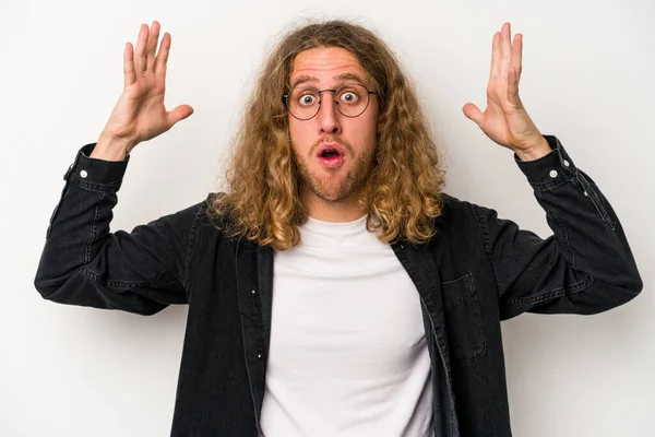 Beyaz arka planda izole olmuş genç beyaz bir adam zaferi veya başarıyı kutluyor, şaşırıyor ve şok oluyor..