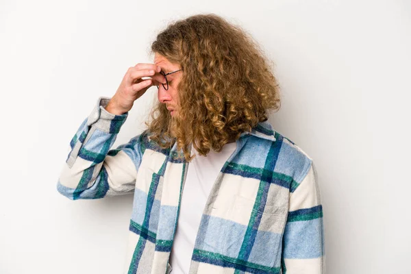 Beyaz arka planda izole olmuş genç beyaz bir adam başı ağrıyor, yüzüne dokunuyor..