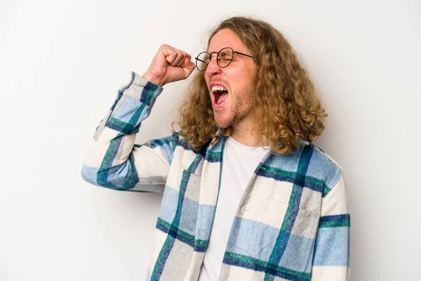 Beyaz arka planda izole edilmiş genç beyaz bir adam zaferi, tutkuyu ve coşkuyu kutluyor, mutlu bir ifade..