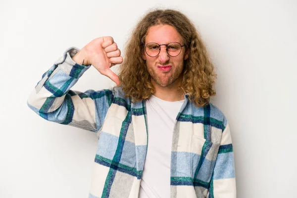 Beyaz arka planda izole edilmiş genç beyaz bir adam baş parmağını aşağı gösteriyor ve hoşlanmadığını ifade ediyor..