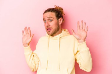 Pembe arka planda izole genç beyaz adam yakın bir tehlike nedeniyle şoka uğruyor.