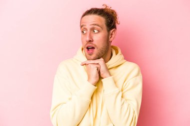 Pembe arka planda izole edilmiş genç beyaz adam şans için dua ediyor, hayrete düşüyor ve ağzını açıp önüne bakıyor..