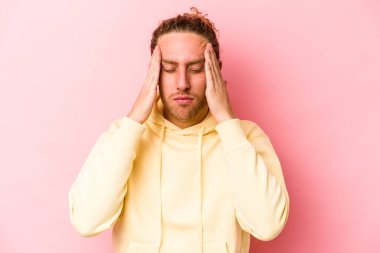 Kafkasyalı genç bir adam pembe arka planda izole edilmiş, başı ağrıyor, yüzüne dokunuyor..
