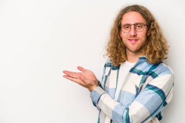 Beyaz arka planda izole edilmiş beyaz tenli genç bir adam palmiyesinde bir kopya alanı tutuyor..