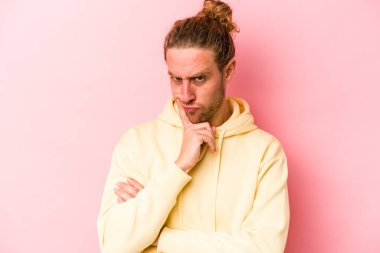 Pembe arka planda izole edilmiş genç beyaz adam bir strateji planlıyor, bir iş yolu düşünüyor..