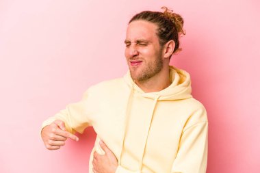 Pembe arka planda karaciğer ağrısı çeken, karnı ağrıyan genç beyaz bir adam..