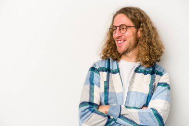 Beyaz arka planda izole edilmiş genç beyaz adam kollarını kavuşturarak gülümsüyor..