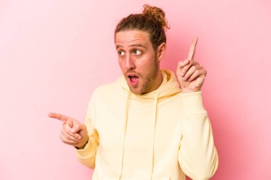 Pembe arka planda izole edilmiş genç beyaz adam farklı fotokopi alanlarını gösteriyor, birini seçiyor, parmaklarıyla gösteriyor..