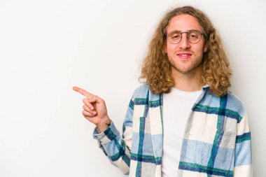 Beyaz arka planda izole edilmiş genç beyaz adam işaret parmağıyla işaret ederek gülümsüyor..