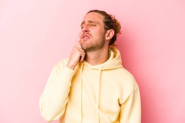 Kafkasyalı genç bir adam pembe arka planda izole edilmiş ağlıyordu, bir şeyden mutsuzdu, acı ve kafa karışıklığı içeriyordu..