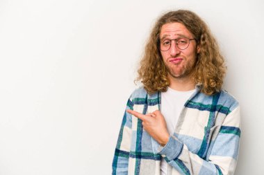 Beyaz arka planda izole edilmiş genç beyaz bir adam gülümsüyor ve boş alanda bir şeyler gösteriyor..