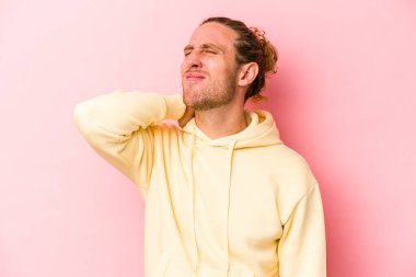 Genç beyaz adam pembe arka planda izole edilmiş dirsek masajı yapıyor, kötü bir hareketin ardından acı çekiyor..