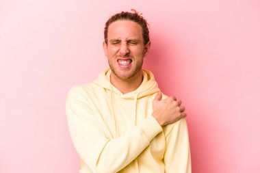 Pembe arka planda izole edilmiş, omuz ağrısı olan genç beyaz bir adam..