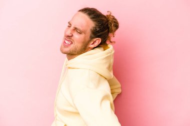 Pembe arka planda izole edilmiş beyaz bir adam sırt ağrısı çekiyor..