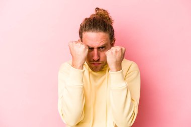 Pembe arka planda izole edilmiş genç beyaz bir adam bir tartışma yüzünden yumruk, öfke, kavga ve boks atıyor..