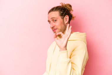 Pembe arka planda izole edilmiş genç beyaz bir adam bir göz kırptı ve elleriyle iyi bir jest yaptı..