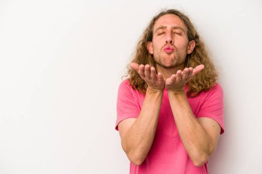 Beyaz arka planda izole edilmiş genç beyaz bir adam dudaklarını katlıyor ve hava öpücüğü vermek için avuç içleri tutuyor..