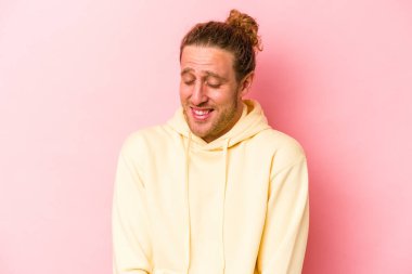 Pembe arka planda izole edilmiş genç beyaz adam gülüyor ve gözlerini kapıyor, rahatlamış ve mutlu hissediyor..