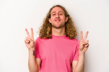 Beyaz arka planda izole edilmiş genç beyaz bir adam zafer işareti gösteriyor ve gülümsüyor..