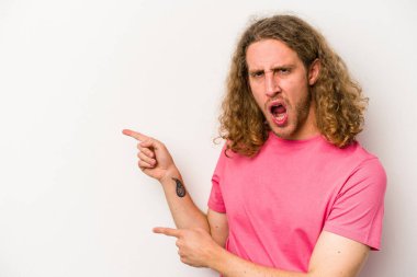 Beyaz arka planda izole edilmiş genç beyaz bir adam işaret parmağıyla fotokopi alanını işaret ederek heyecan ve arzusunu ifade ediyor..