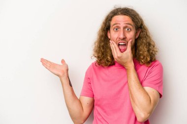 Beyaz arka planda izole edilmiş genç beyaz bir adam bir avuç içinde fotokopi alanı tutuyor, el üstünde tutuyor. Şaşırmış ve mutlu..