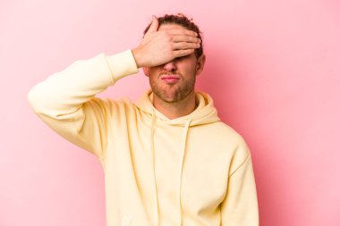 Pembe arka planda izole edilmiş genç beyaz adam tapınaklara dokunuyor ve baş ağrısı çekiyor..