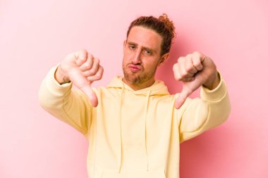 Pembe arka planda izole edilmiş genç beyaz bir adam hoş olmayan bir jest yapıyor. Anlaşmazlık konsepti.