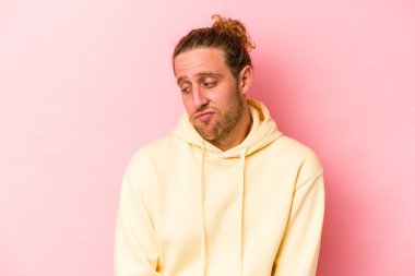 Pembe arka planda izole edilmiş genç beyaz adam omuzlarını silkeliyor ve gözleri açık..