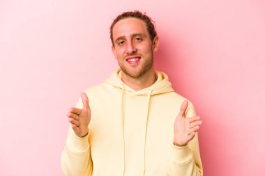 Pembe arka planda izole edilmiş beyaz bir adam iki eliyle bir şey tutuyor, ürün sunumu..