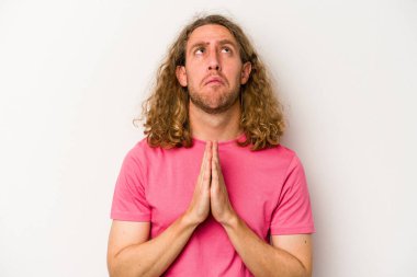 Beyaz arka planda izole edilmiş genç beyaz bir adam el ele tutuşup, ağız kenarında dua ediyor, kendinden emin..