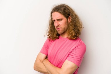 Beyaz arka planda izole edilmiş, hoşnutsuzca kaşlarını çatmış, kollarını kavuşturmuş genç beyaz bir adam..