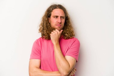 Beyaz arka planda soyutlanmış genç beyaz bir adam kafası karışmış, şüpheli ve güvensiz hissediyor..