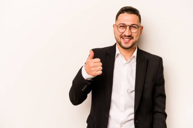 Beyaz arka planda izole edilmiş İspanyol bir adam gülümsüyor ve başparmağını kaldırıyor.