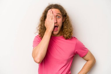 Beyaz arka planda izole edilmiş genç beyaz bir adam yüzünün yarısını palmiye ile örterek eğleniyor..